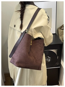 Détail du sac seau en daim marron foncé avec boucle dorée et bandoulière en cuir