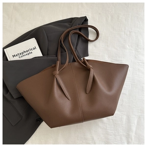 Detail of dark coffee litchi grain leather tote bag with elegant side wing design