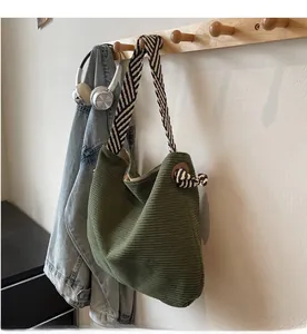 Close-up of green corduroy hobo bag featuring vertical texture and a striped shoulder strap