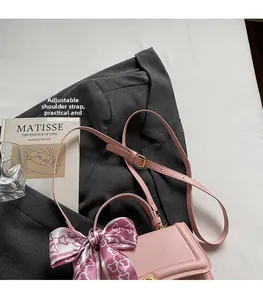 Pink tote bag detail with adjustable strap and decorative silk scarf on a grey blazer