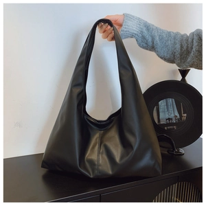 Minimalist black faux leather hobo bag with wide shoulder strap shown in a clean studio setting