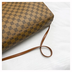 Close-up of brown litchi grain leather tote bag with geometric print and logo detail