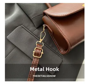Detailed close-up of dark brown leather handbag with gold metal hook and strap