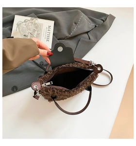 Detail view of brown faux shearling bag featuring leather handles and magnetic flap closure