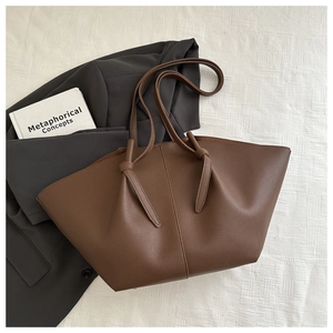 Close-up of deep brown lychee grain leather tote bag with unique knotted handle design