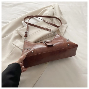 Detail view of brown vintage shoulder bag with silver rivets and metal buckle on white fabric
