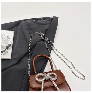 Détail d'un sac en cuir marron avec double nœud en strass argenté et chaîne élégante