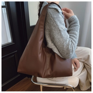 Minimalist brown oversized tote bag in matte leather featuring vertical side seam stitching