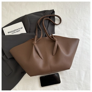 Detail of dark brown lychee texture leather tote bag with unique knot shoulder strap accents