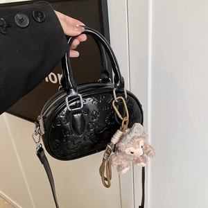Sac bowling noir élégant avec gaufrage, texture cuir et breloque en peluche mignonne