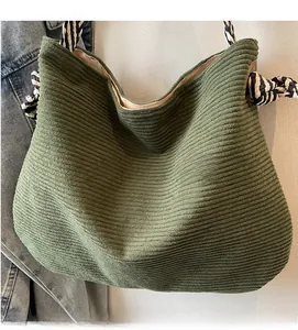 Detail view of green corduroy tote bag with textured stripes and braided rope strap