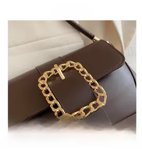 Detailed view of the dark brown leather square bag with a large golden chain buckle