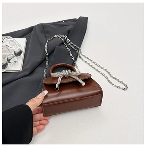 Détail du petit sac carré marron avec nœud en strass argenté et bandoulière en chaîne
