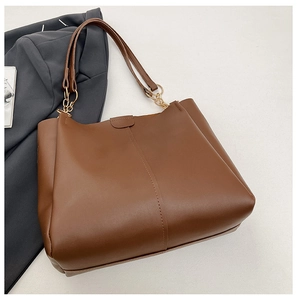 Detail of caramel leather tote bag with vertical stitching and gold metal chain links