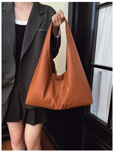 Close-up of caramel orange tote bag featuring vertical stitching and matte PU texture