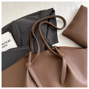 Detail of caramel leather tote with small pouch showing high-quality lychee grain texture