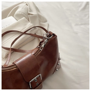 Detail view of brown vintage shoulder bag with metal rivets and decorative belt buckle