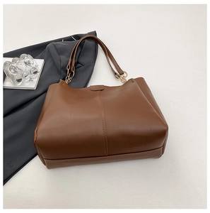 Detailed close-up of brown leather tote bag with vertical stitching and metallic rings
