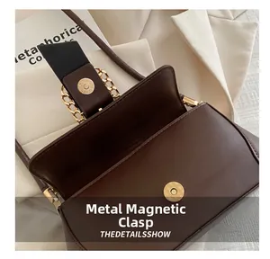 Detail shot of a dark brown leather bag showing the golden magnetic snap and chain strap