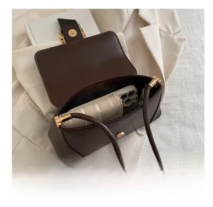 Interior storage space of a dark brown shoulder bag with magnetic gold clasp and smartphone