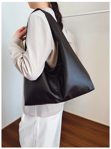 Detail view of large black matte PU leather hobo tote bag worn by a model on shoulder