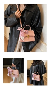Detailed view of pink crossbody bag with gold ring buckle and decorative silk scarf handle