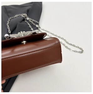 Vue détaillée du sac en cuir marron avec coutures précises et boucle nœud en métal argent