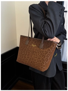 Detail of leopard print tote bag with gold lettering and brown leather shoulder straps