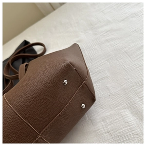 Close-up of brown pebbled leather tote bag base with silver anti-wear metal studs