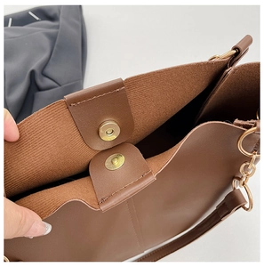 Close-up of magnetic buckle and golden metal ring on brown leather shoulder bag
