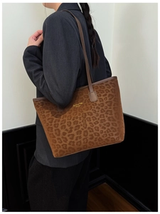 Side view of a large leopard print bucket tote bag worn by a model for a stylish look