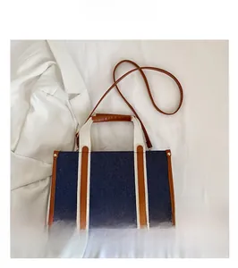 Detailed top view of denim and leather tote bag with dual handles on white fabric