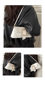 Detail of off-white leather shoulder bag with gold chain buckle and modern strap design