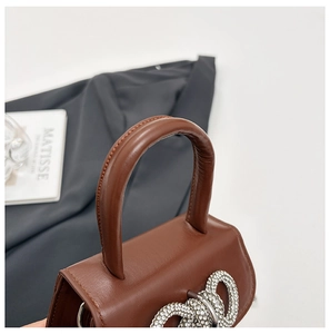 Gros plan d'un sac en cuir marron avec un grand nœud en strass et des coutures de précision