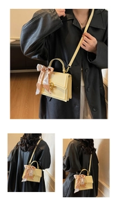 Detail of light yellow small square bag featuring a printed silk scarf and gold metal lock