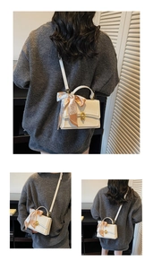 Detail of white leather handbag featuring gold twist lock and elegant silk scarf handle