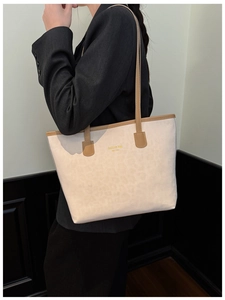 Detail of cream leopard print bucket bag with brown leather trim and gold logo
