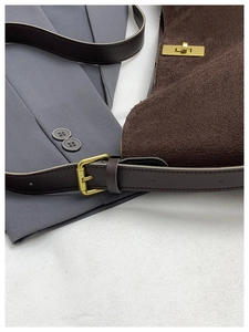 Détail du sac à main en cuir mat marron foncé avec boucle dorée et bandoulière réglable