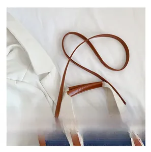 Detail view of denim tote bag with contrast brown leather straps and fabric handles