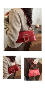 Detail view of red square handbag featuring a bold gold chain buckle and leather strap