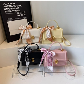 Detail view of four colorful PU leather crossbody bags with silk scarves and metal locks