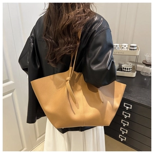 Detail of light brown lychee leather tote bag featuring stylish knotted strap accents