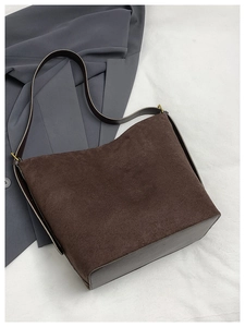 Détail de la bandoulière en cuir avec boucle dorée sur un sac cabas en daim marron