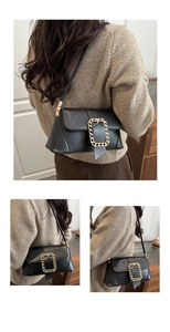 Detailed view of black leather baguette bag with gold chain buckle and shoulder strap