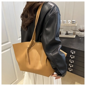 Brown litchi grain leather tote bag shown on model in a modern indoor setting