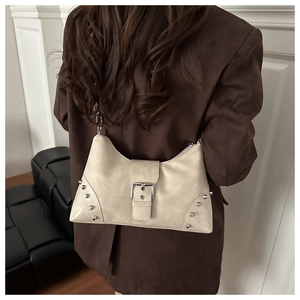 Detail view of cream shoulder bag with silver studs and retro buckle on a brown blazer
