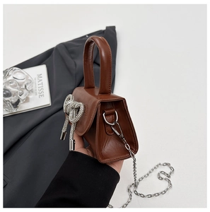 Détail de vue latérale d'un mini sac à main marron avec nœud en strass argenté en cœur