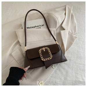 Detail of dark brown leather baguette bag with a signature gold chunky chain buckle