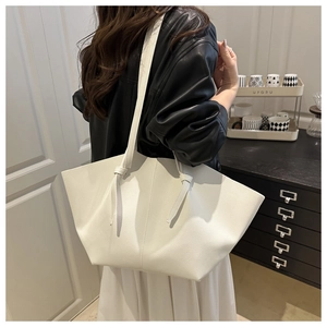 Close-up of white minimalist oversized tote bag with knot strap detail and pebble texture