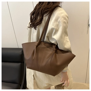 Brown lychee leather tote bag featuring elegant vertical stitching and decorative knotted straps